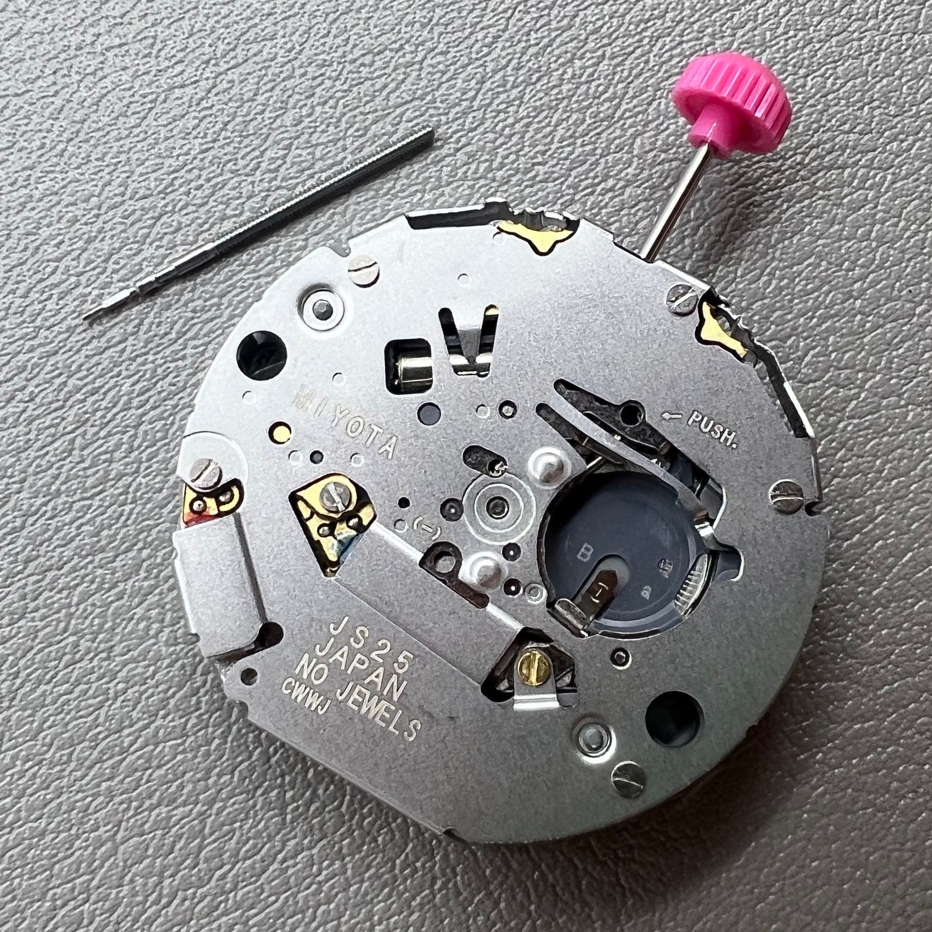 Japan Miyota JS25 watch movement close-up showing small second subdials at 3, 6, and 9 o'clock positions.