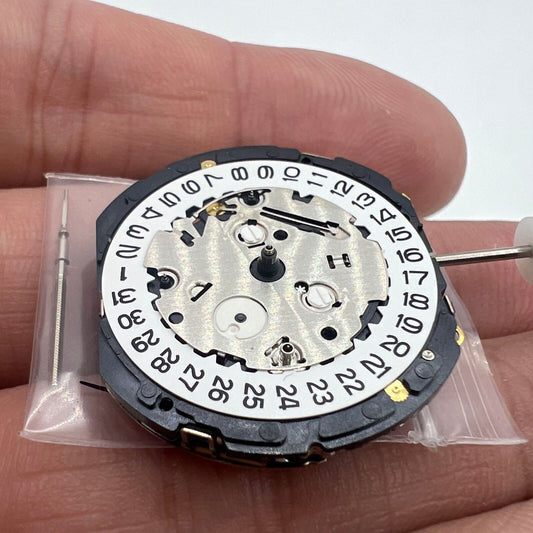 Orient KFB00 quartz watch movement with date at 3, white disk, Japan-made replacement part for precise timekeeping.
