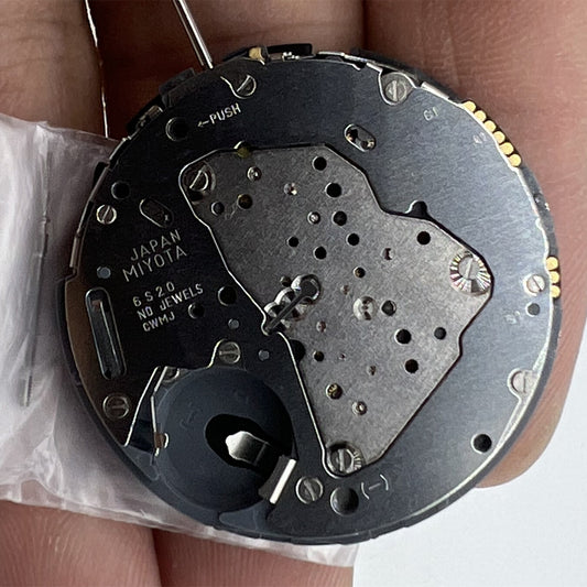 Miyota 6S20 quartz watch movement showing date at 3, three hands, and small second dial at 6 and 9 positions.