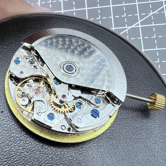 Dandong 7750 watch movement close-up showing date at 3 and small seconds at 6, 9, 12 markers.