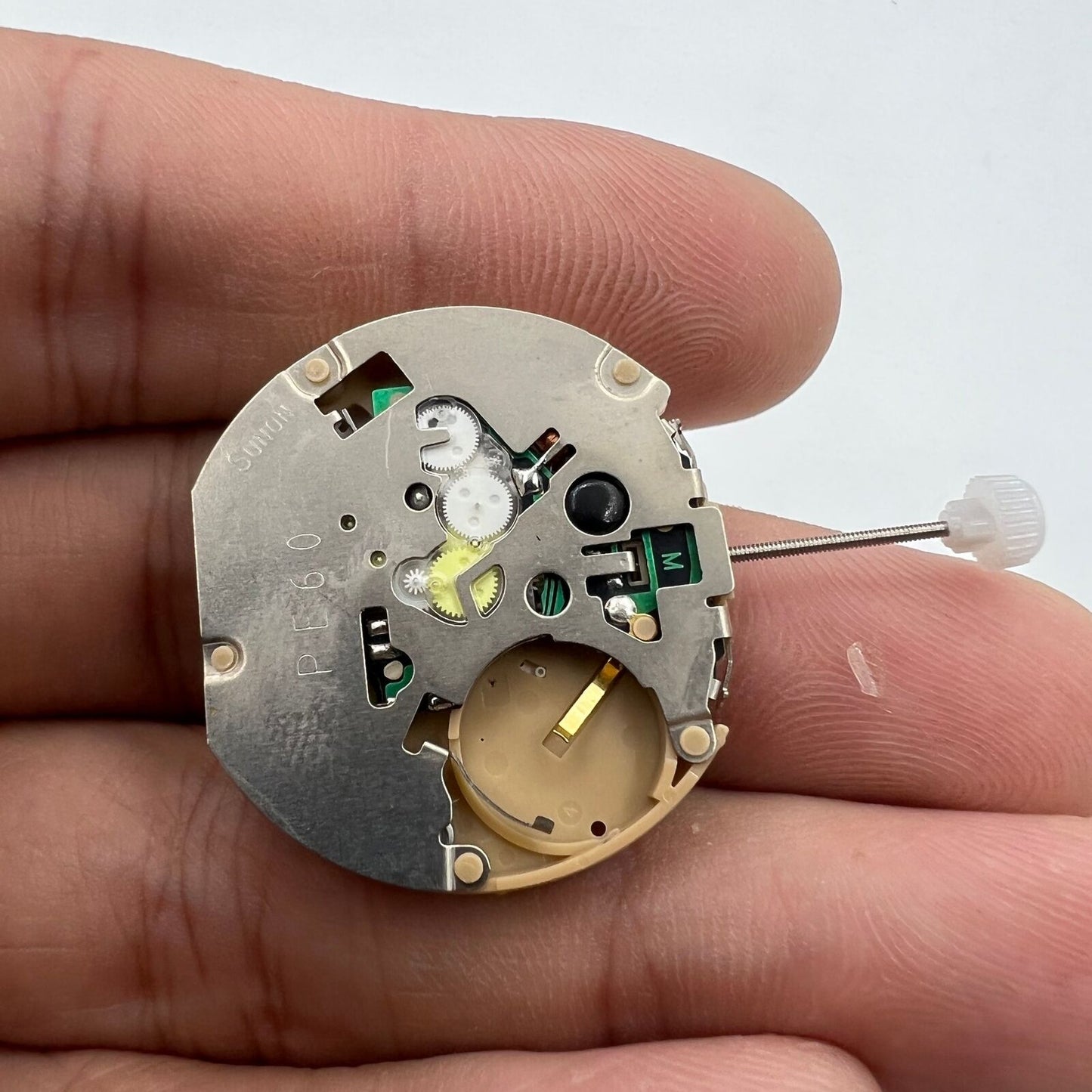 Sunon PE60 quartz watch movement with date window at 6 o'clock, precise three-hand timekeeping.