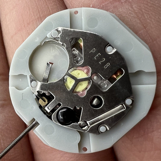 Sunon PE28 quartz watch movement with date at 6 and three hands for precise timekeeping.