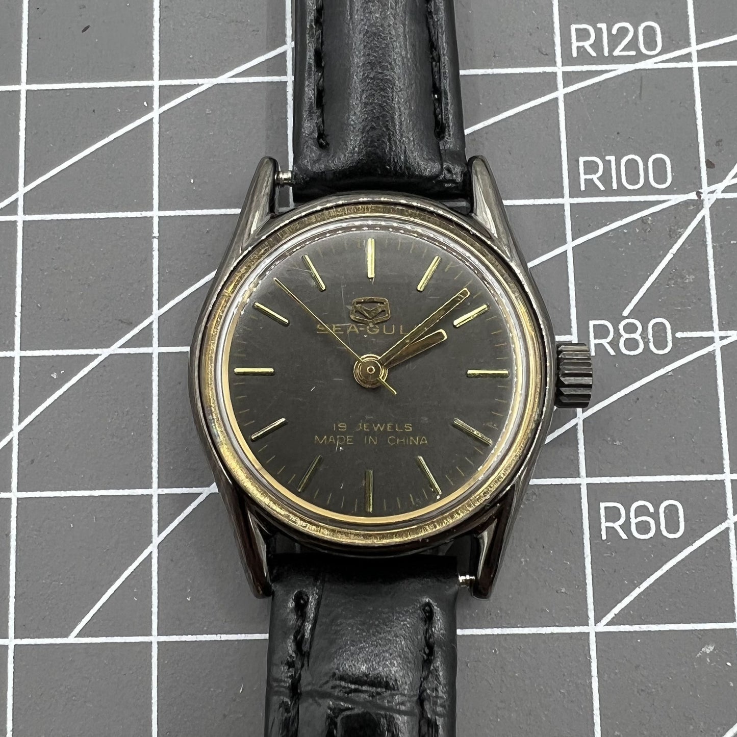Seagull black case ladies manual mechanical watch with gold nail markers, shock-resistant for lasting durability.