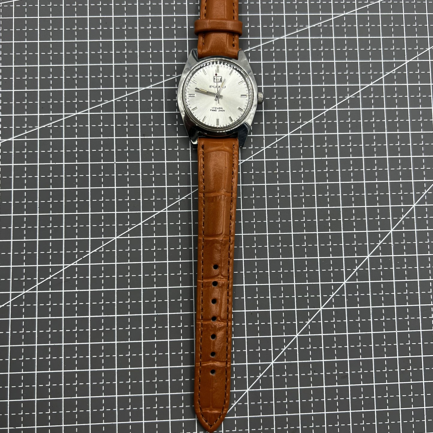 PUBU 32mm manual mechanical watch with grey dial, 17 jewels, and elegant nail indices showcasing Chinese craftsmanship.