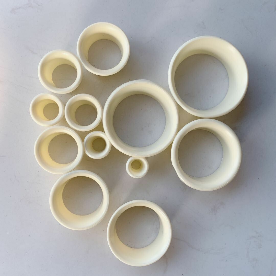 Stacked set of 12 plastic watch movement holder cases for organized watch repair storage.