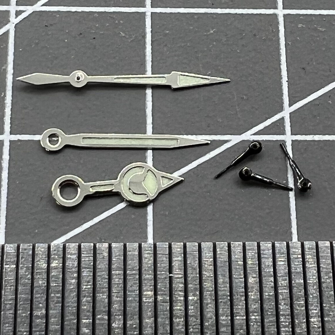 Black 12mm watch hands with silver trim and green luminous finish for Miyota 0S60, ideal for precise timekeeping.