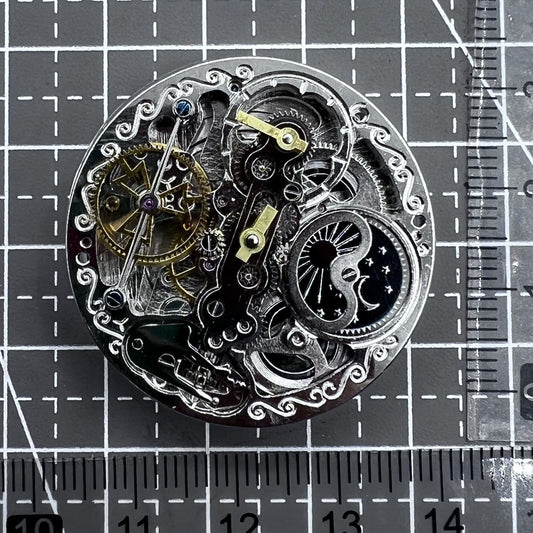 Silver hollow movement watch accessory with small bare balance wheel at 6 o'clock, featuring double mainspring by Double Mainspring.