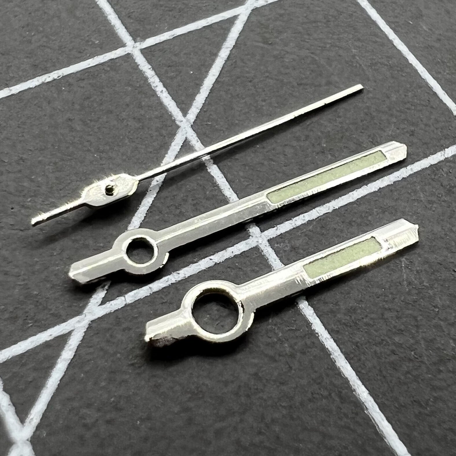 Green luminous watch hands with silver trim, compatible with Orient 46941/46943 movements, perfect for timepiece repairs.