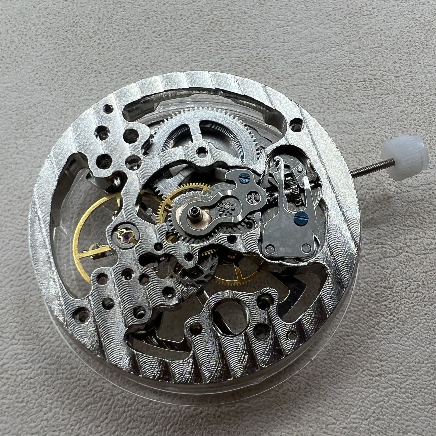 Hollow silver manual winding watch movement, highlighting precise mechanical craftsmanship.