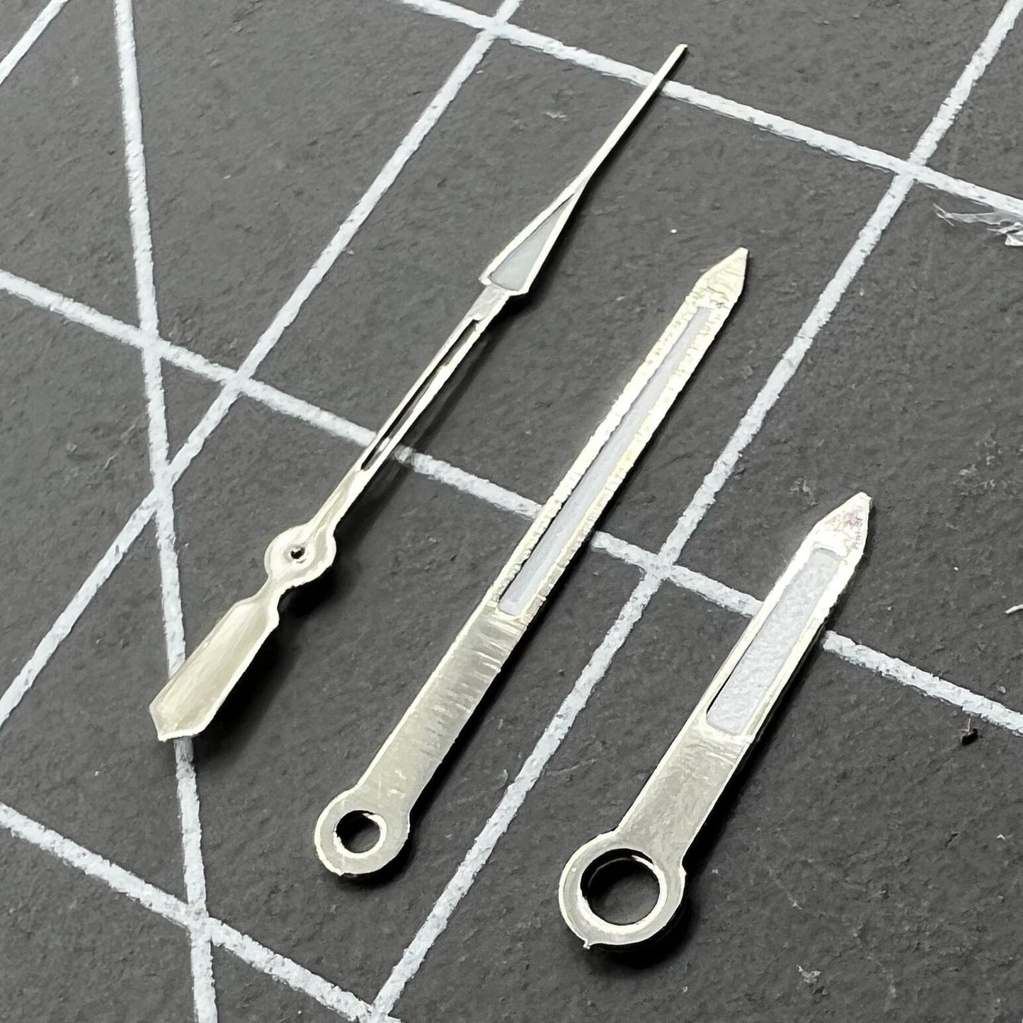 Silver-trimmed 14mm watch hands with green lume, fits Ronda 515 quartz for stylish timekeeping.