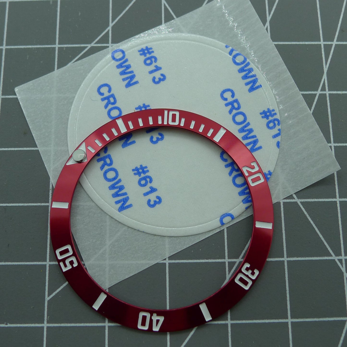 38mm ceramic watch bezel with red ring, silver font, and green luminous markers.