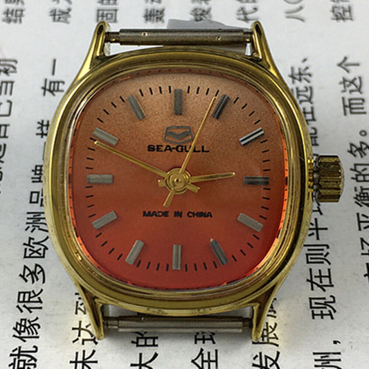 Seagull 27mm square gold case ladies watch with manual mechanical movement on orange background.