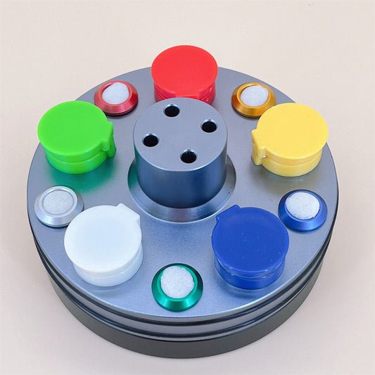 Metal oil cups set with plastic covers on rotating stand for watch repair, ideal for precise lubrication by brand.