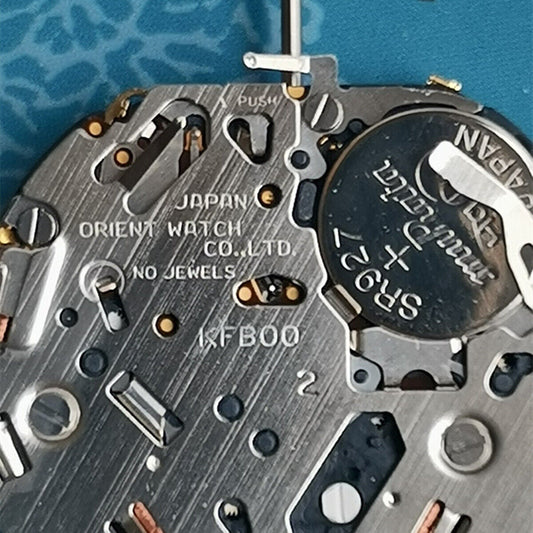 Orient KFB00 quartz watch movement with date at 3, white disk, Japan made for precise timekeeping.