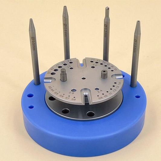 Blue rotated stand holding watch balance staff and hairspring, precision repair tool for watchmakers.