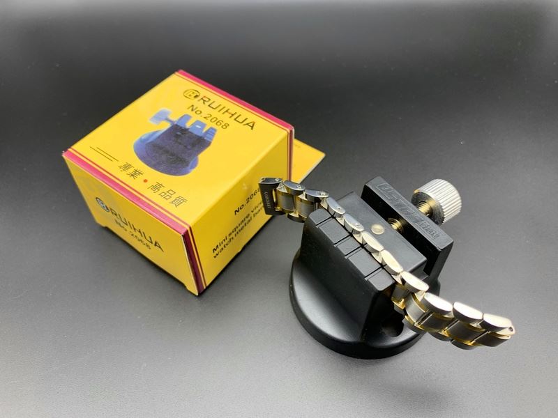 Watch band link remover tool with hammer and pins for precise bracelet repair.