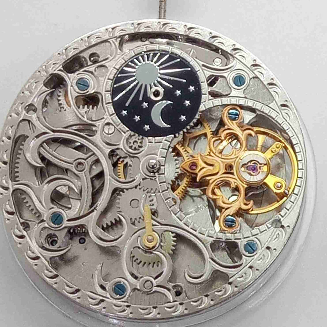 Silver hollow mechanical watch with moonphase at 3 o'clock and large flywheel, China-made craftsmanship.