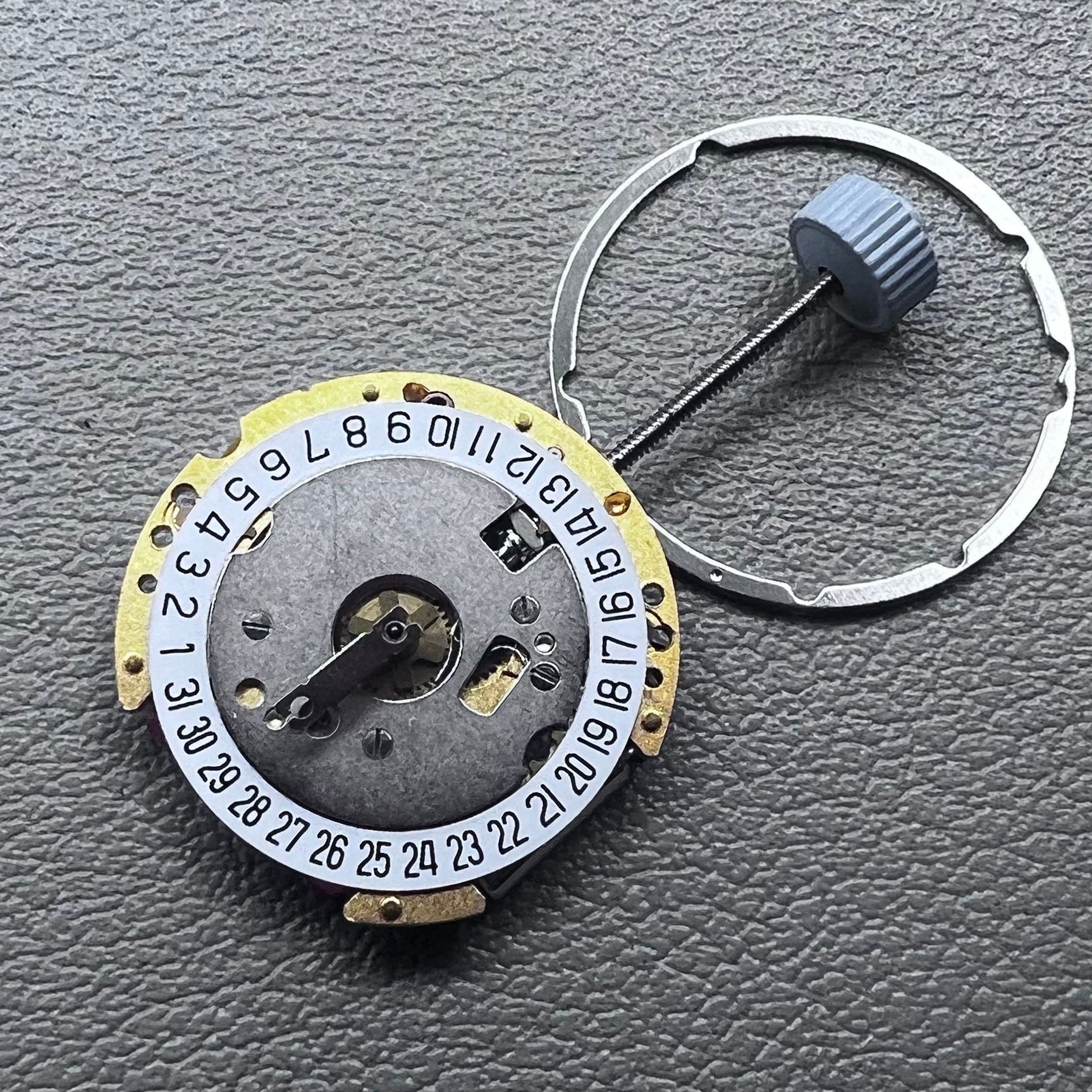Swiss Ronda 775 quartz watch movement with golden finish, date at 6, and three hands.