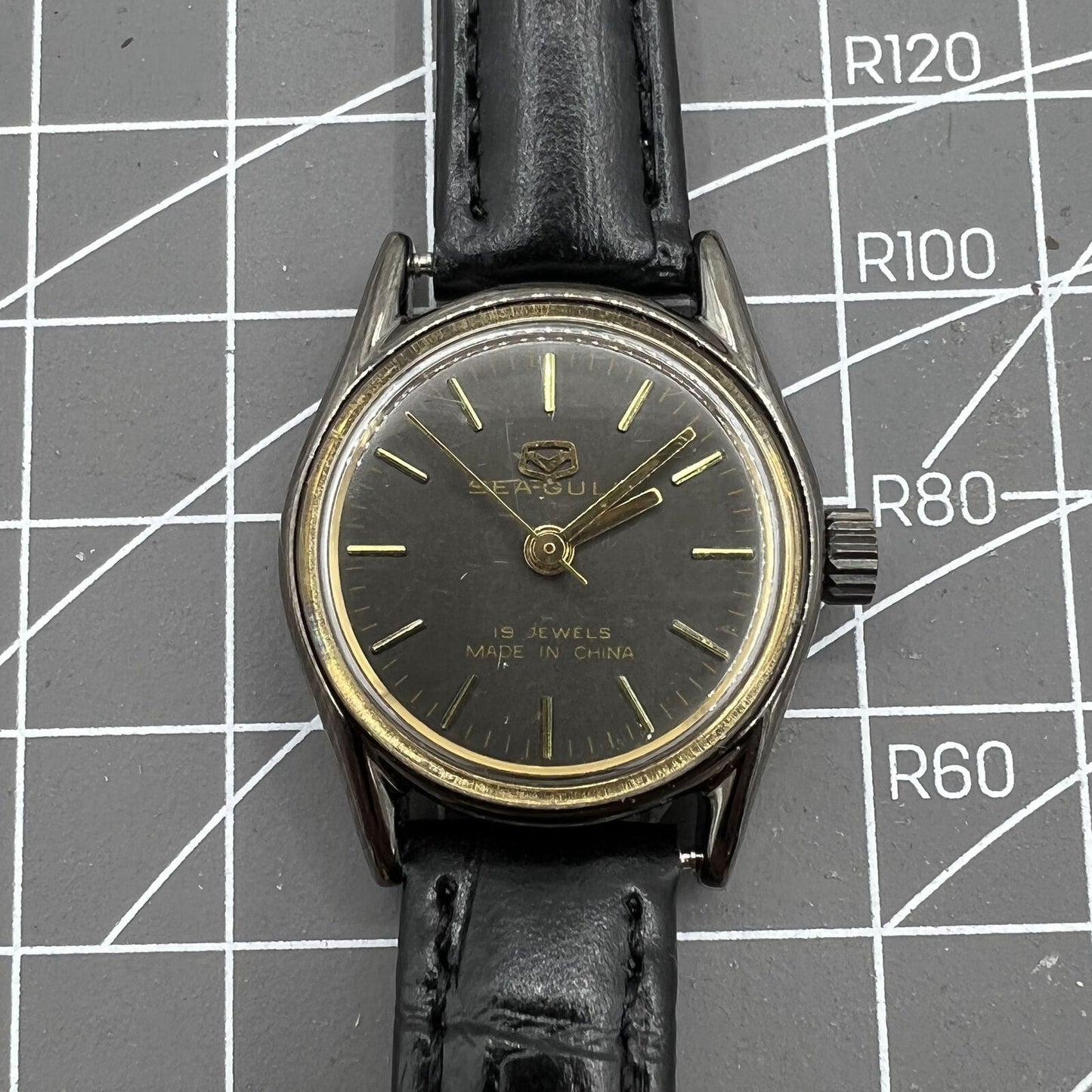 Seagull black case ladies watch with gold nail markers, manual mechanical movement, shock-resistant design.