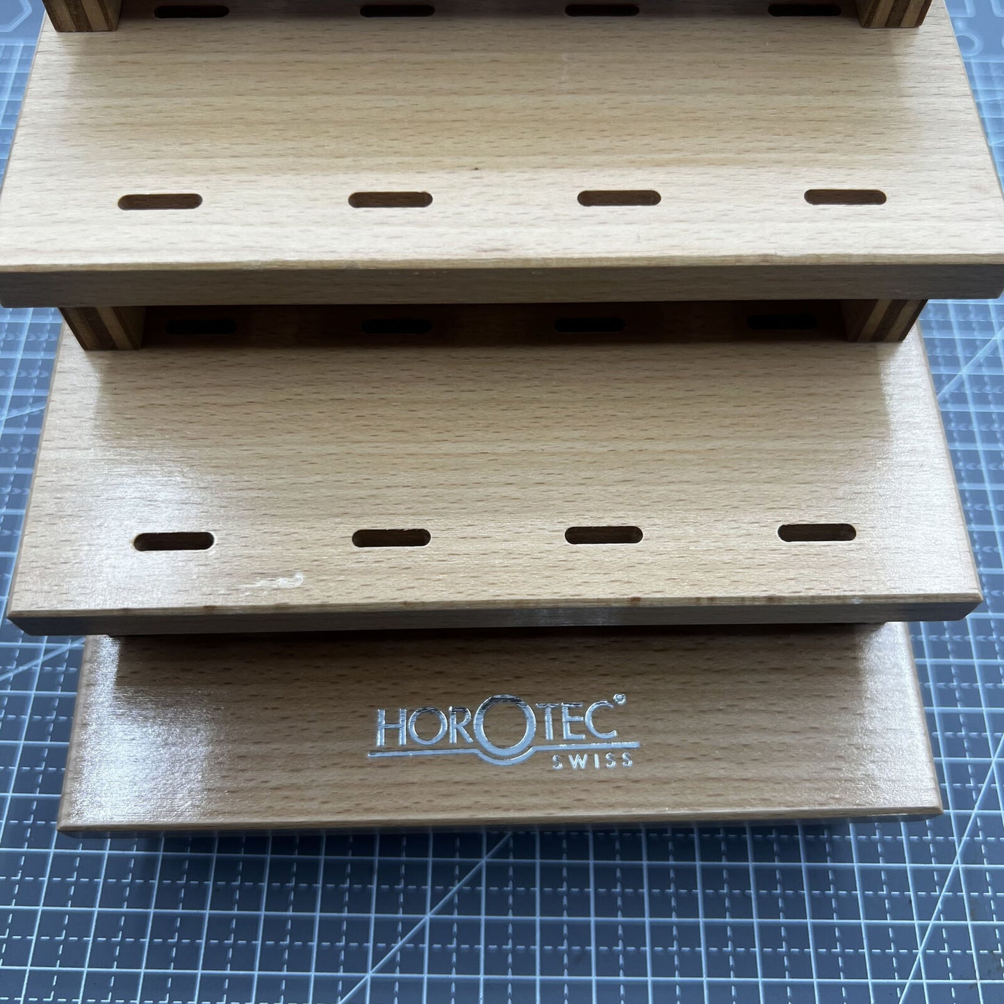Swiss Horotec wooden rack storing 12 precision watchmaker tweezers for tidy tool organization.