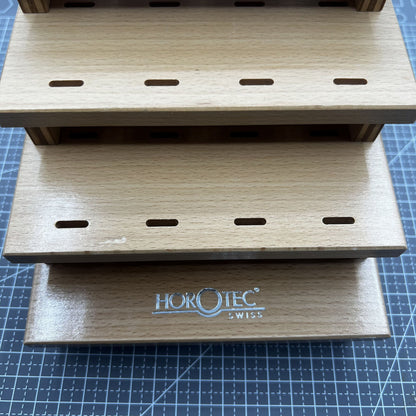 Swiss Horotec wooden rack storing 12 precision watchmaker tweezers for tidy tool organization.