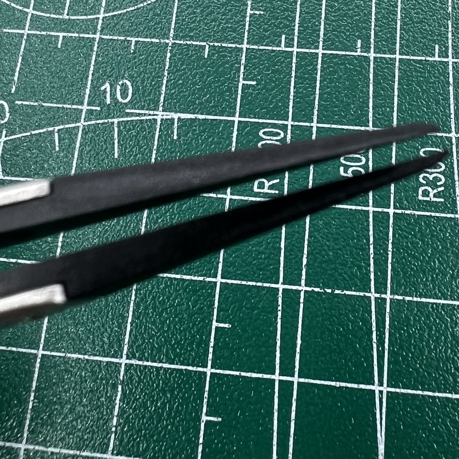 Stainless steel tweezers with carbon fiber tip for precise watch repairs.