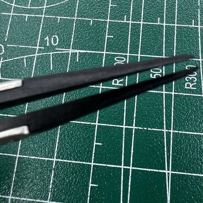 Stainless steel tweezers with carbon fiber tip for precise watch repairs.