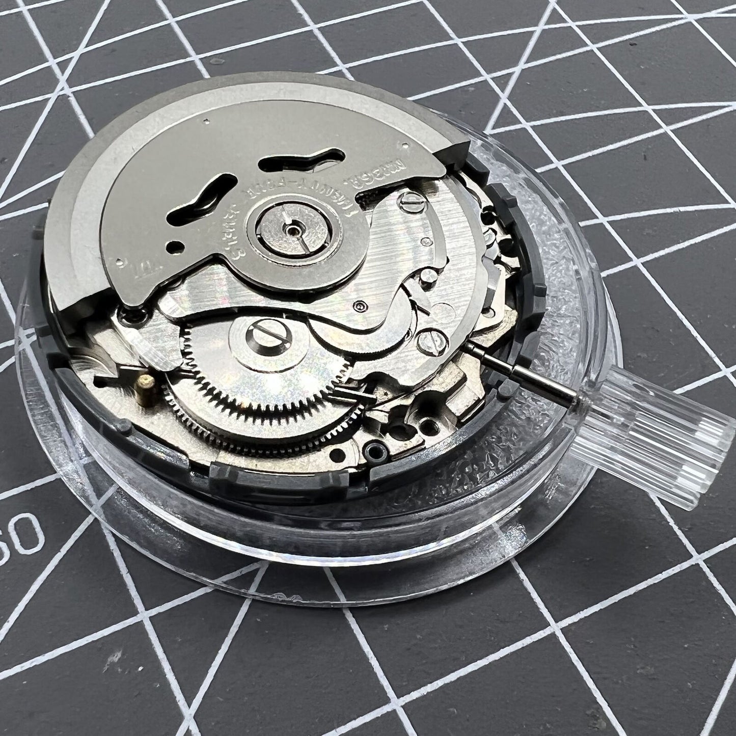 Miyota NH36A automatic watch movement with black finish, blue lume, and crown at 3:38 position for accuracy.