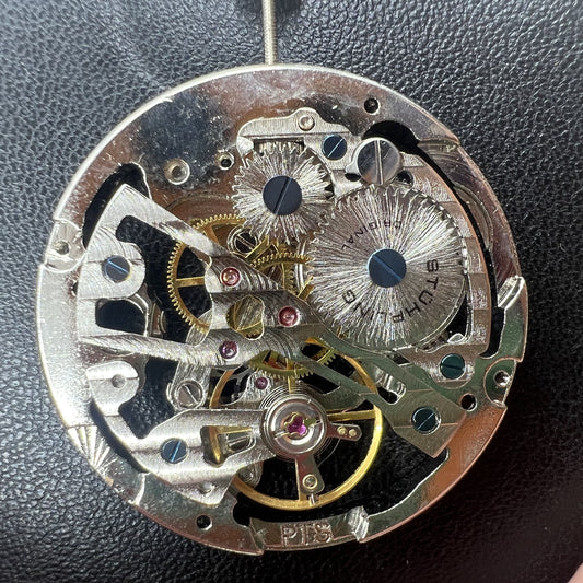 Hollow silver manual winding watch movement showcasing intricate mechanical design.