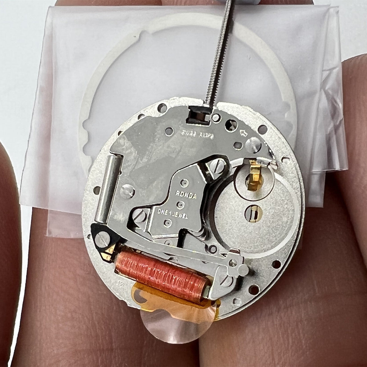 Close-up of golden silver-gilted Swiss RONDA 785 quartz calendar movement for watch accessory repair.