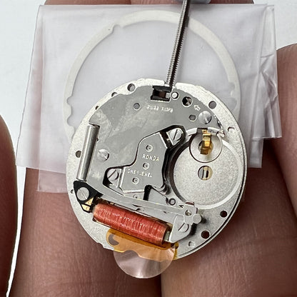 Close-up of golden silver-gilted Swiss RONDA 785 quartz calendar movement for watch accessory repair.