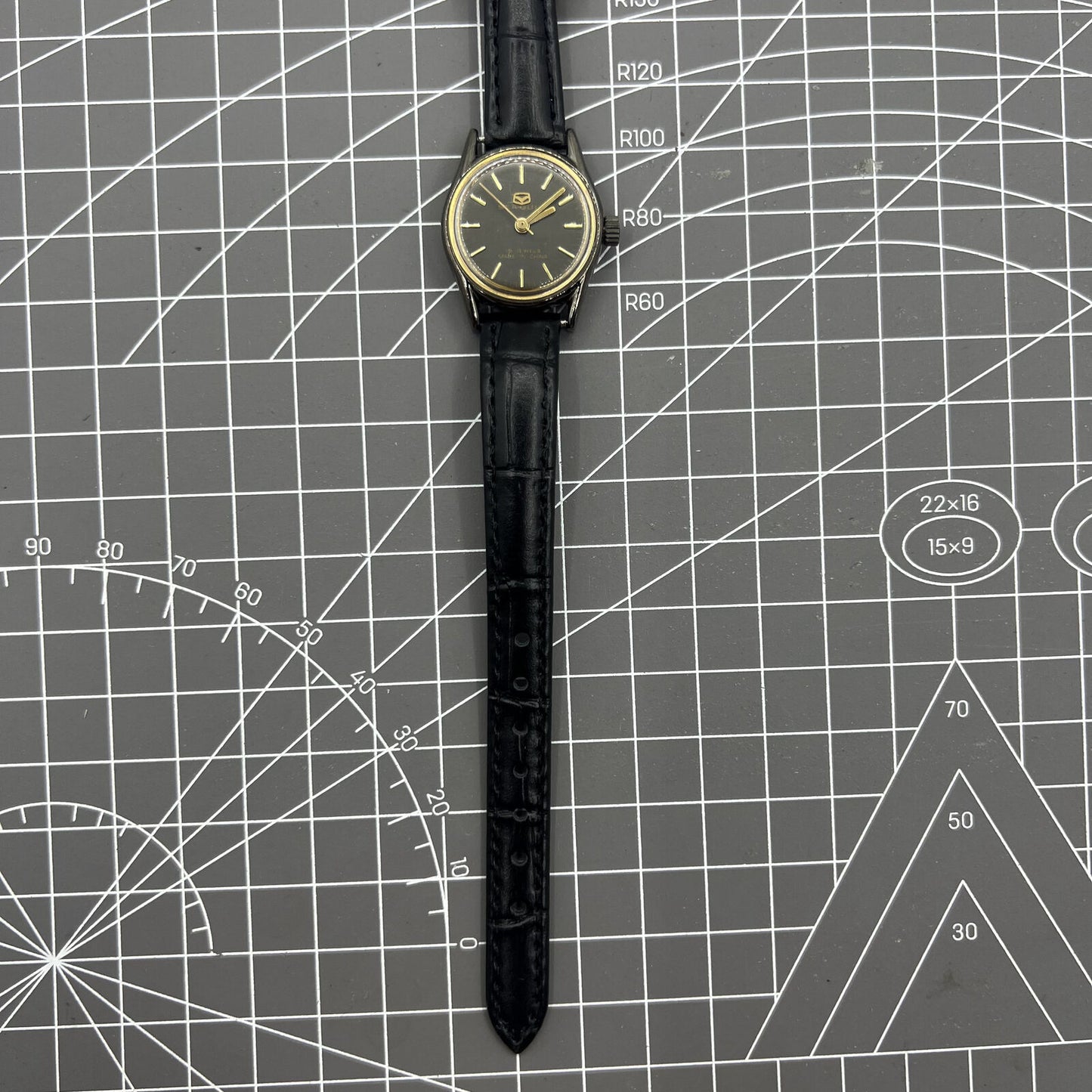 Seagull black case ladies watch with gold nail markers, manual mechanical movement, and shock resistance.