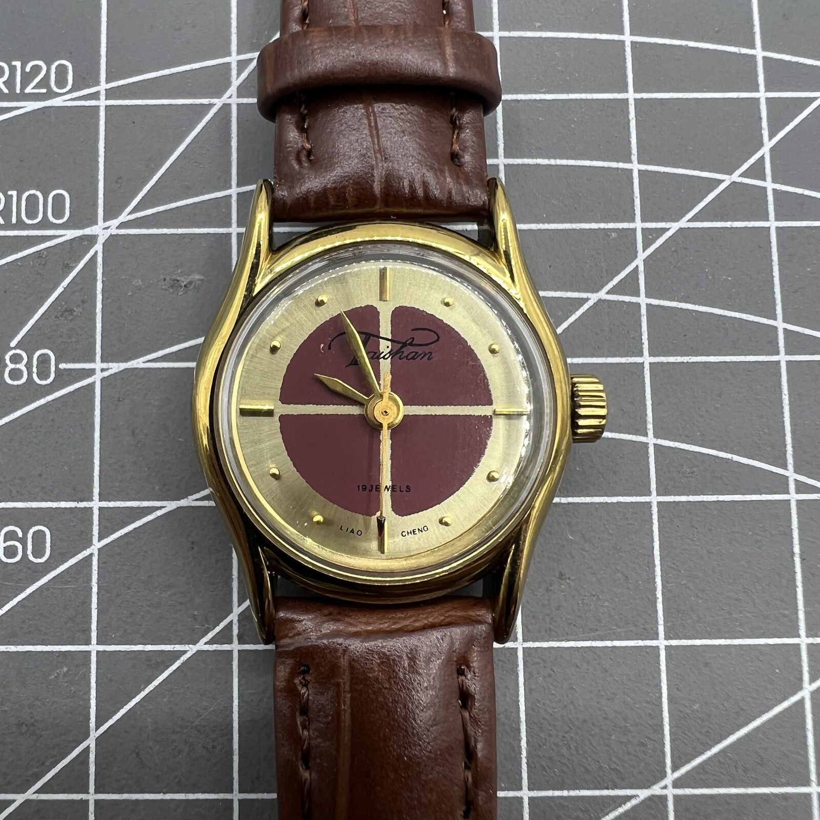 Brown 26mm Liaocheng TAISHAN manual mechanical lady watch with 19 jewels and golden nail accents for elegant style.