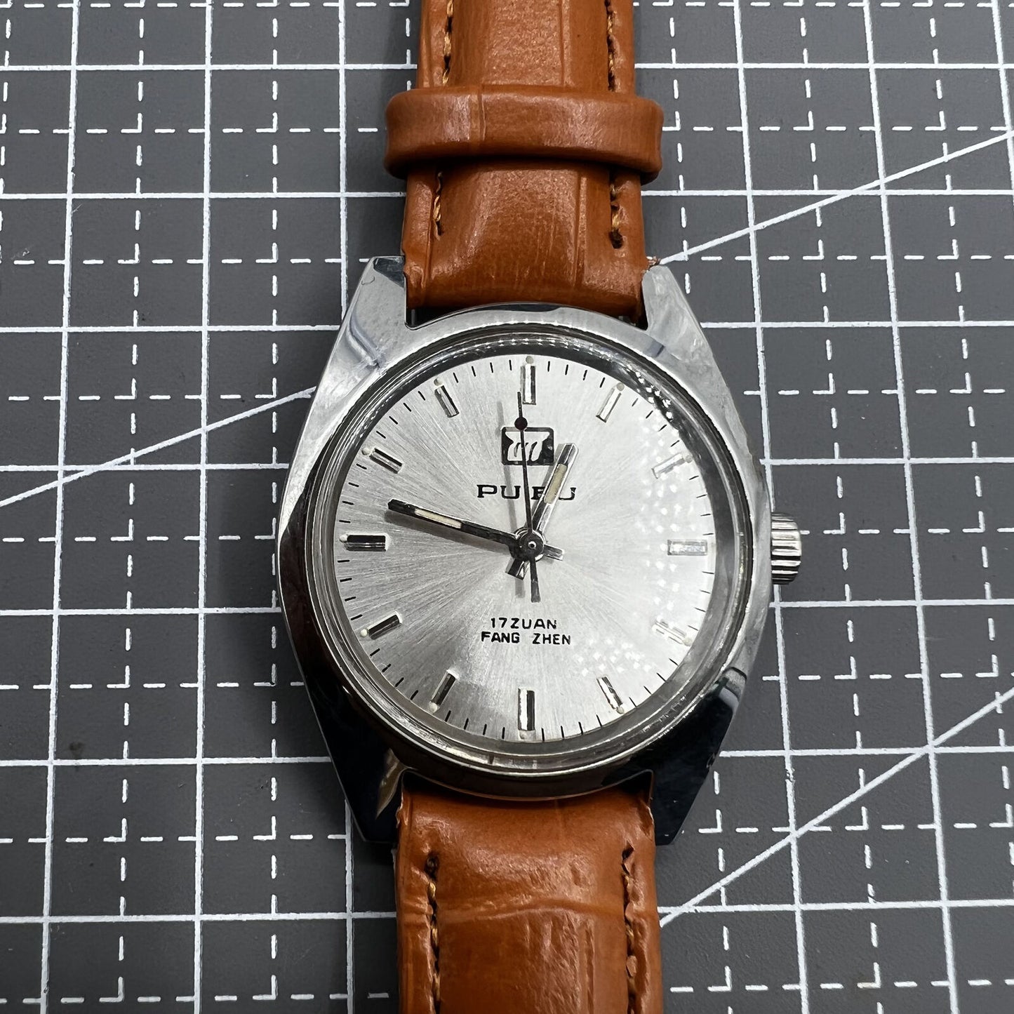 PUBU 32mm manual mechanical watch with grey dial, nail markers, 17 jewels, showcasing precision craftsmanship.