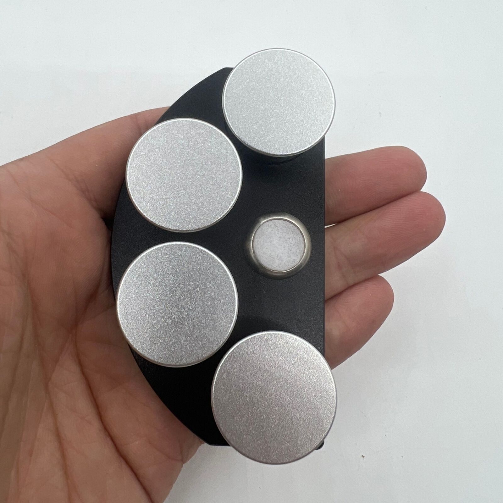 Die-cast alloy oil cup stand holding 4 black ceramic containers for organized watch accessory storage.