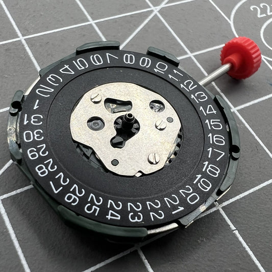 Miyota 2115 quartz movement with date at 3, black disk calendar, and three hands for precise time.