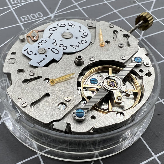 Automatic mechanical watch with reversed balance wheel and big date display at 12, showcasing precision craftsmanship.