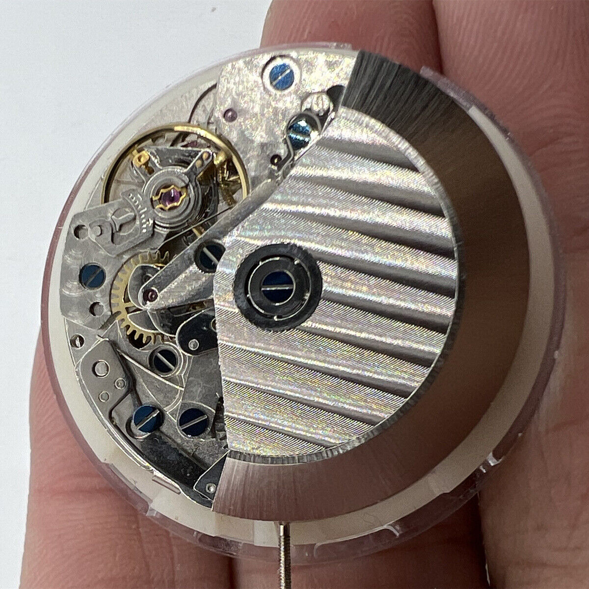 Close-up of Asian 7750 automatic chronograph movement with white calendar at 4:30 and seconds subdial at 9, showcasing precision watch components.