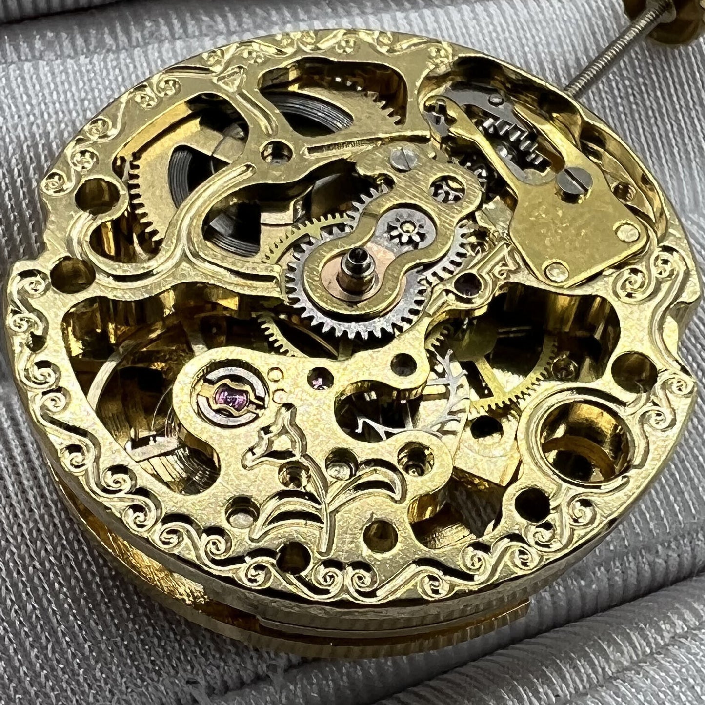 Golden 26.5mm 7120 automatic watch movement with intricate carved hollow design, precision