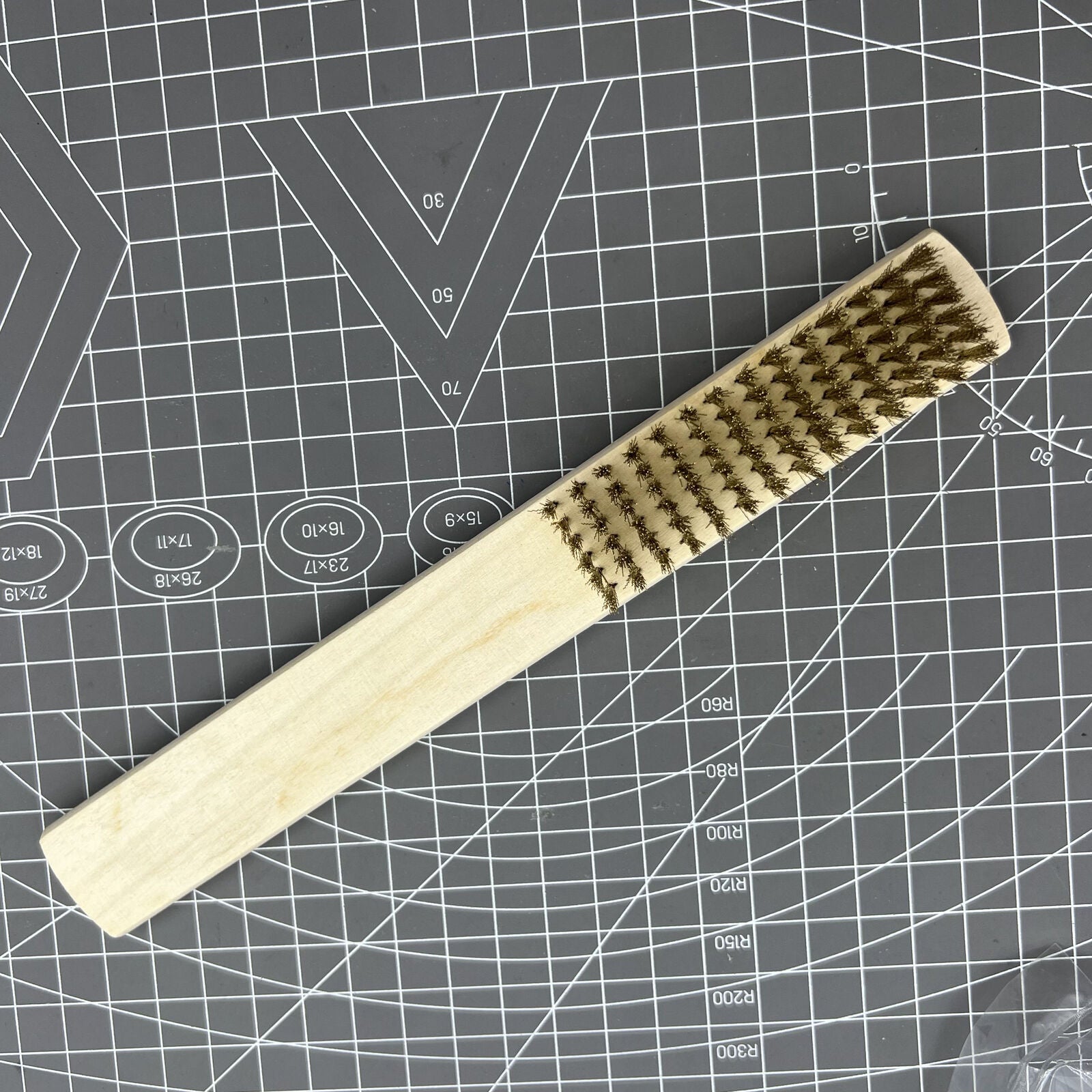 Copper wire brush with wooden handle for rust removal and metal cleaning, ideal for jewelry making tools.
