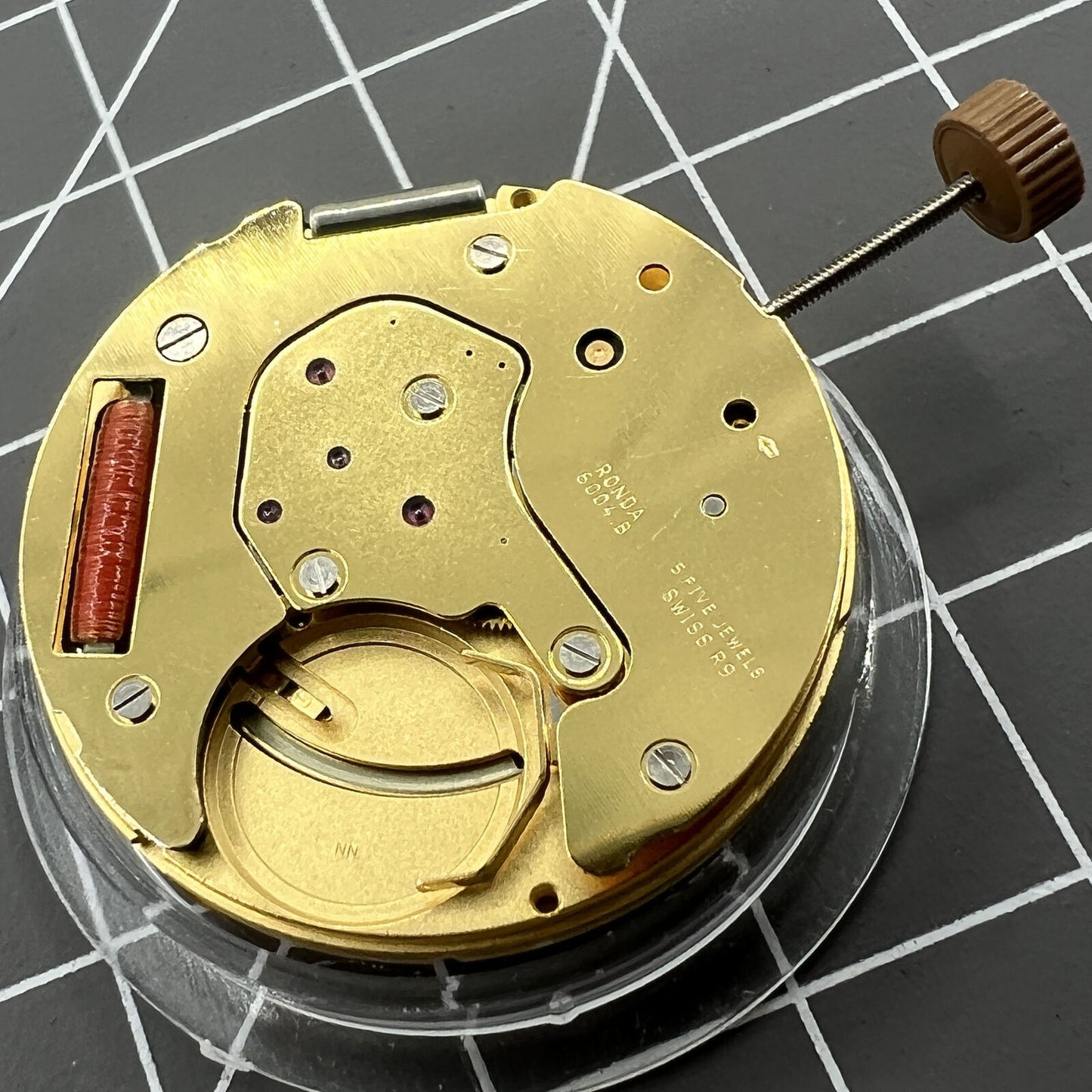 Golden Swiss Made Ronda 6004B quartz watch movement with date display at 12 o'clock, precise timekeeping by Ronda.