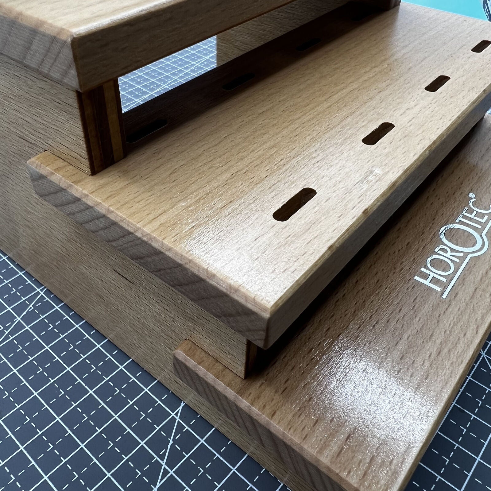 Swiss Horotec wooden rack organizing 12 precision watchmaker tweezers for efficient workshop storage.