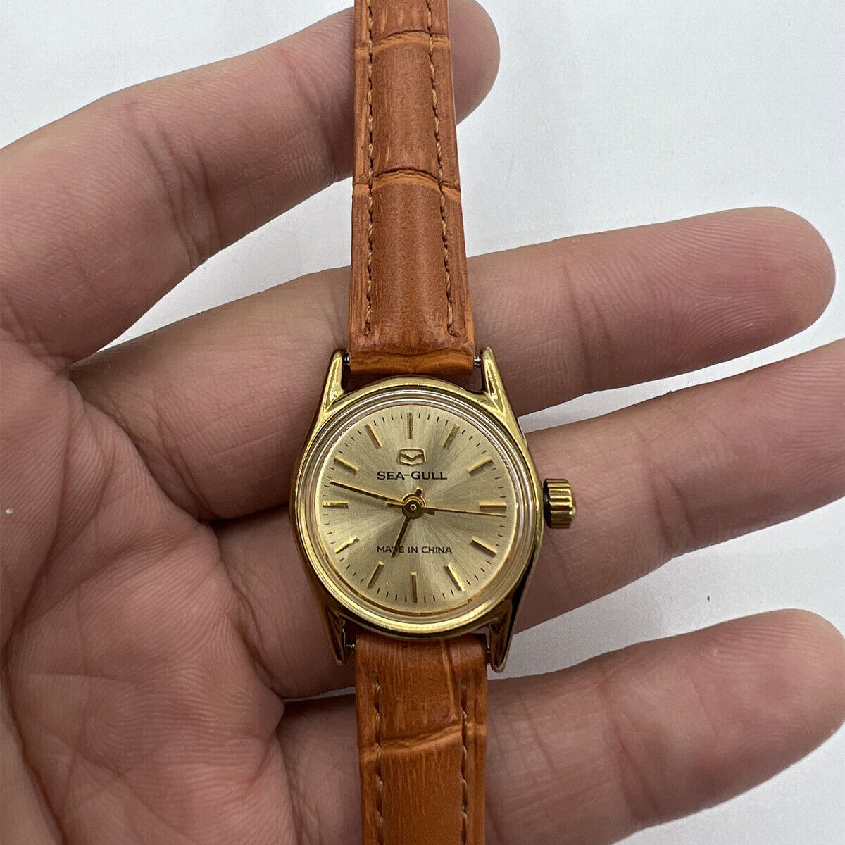 Round golden case ladies watch by China Tianjin Seagull with manual mechanical movement, elegant nail markers.