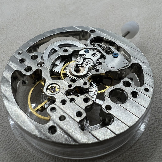 Hollow silver manual winding watch movement showcasing intricate mechanical design.