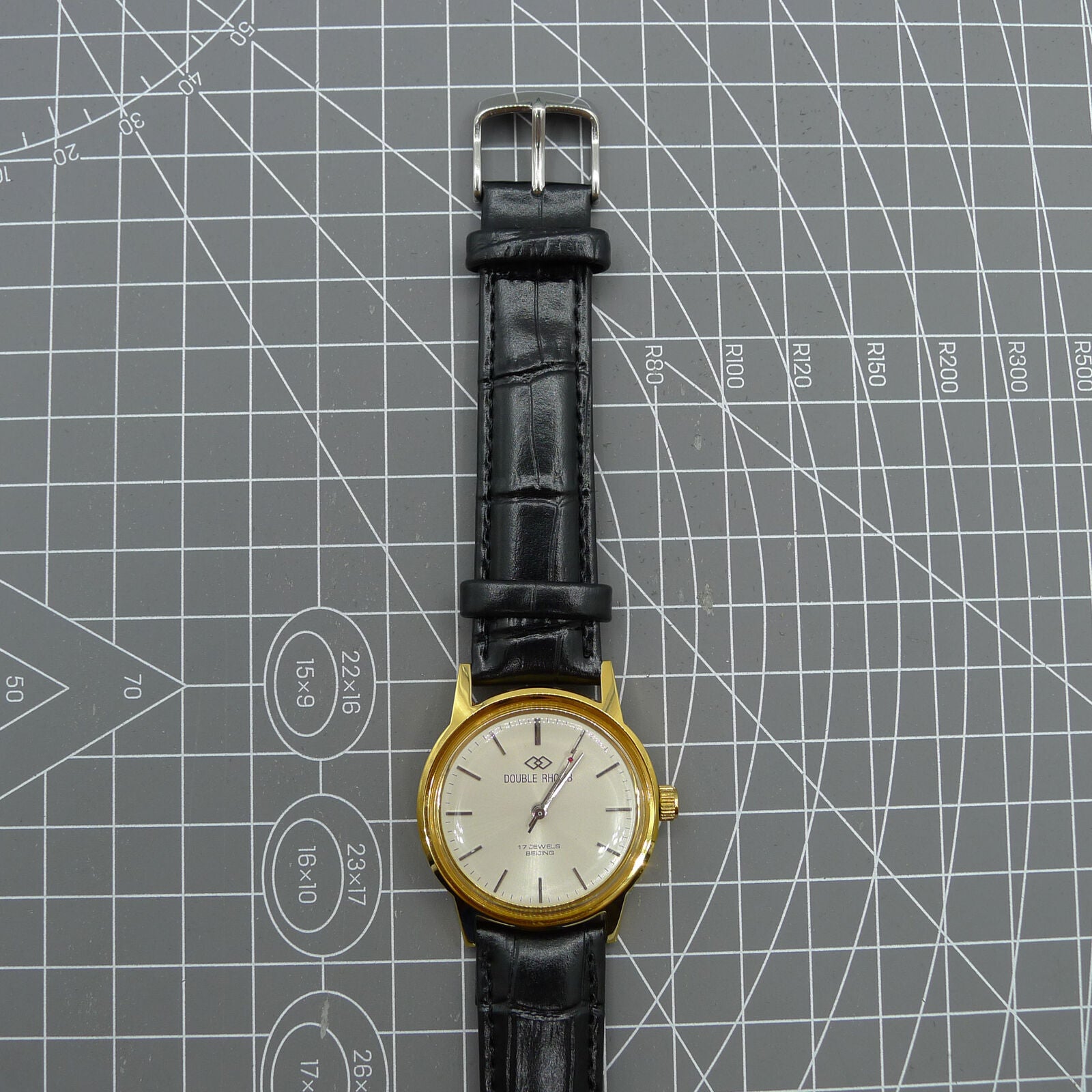 Beijing Double Rhomb watch with golden case, silver nail markers, manual mechanical movement, classic elegance.