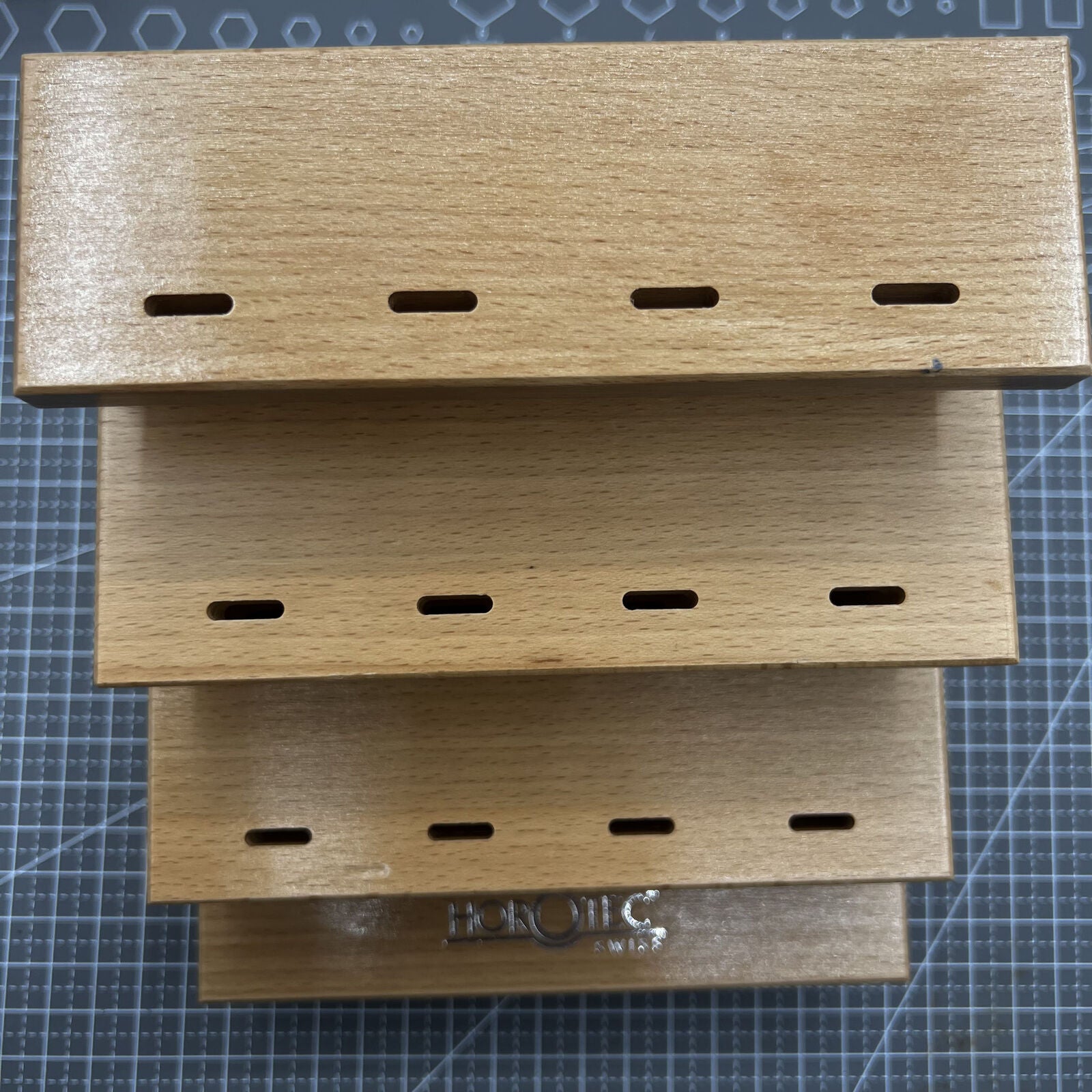 Swiss Horotec wooden storage rack holding 12 watchmaker tweezers, perfect for organized tool storage.
