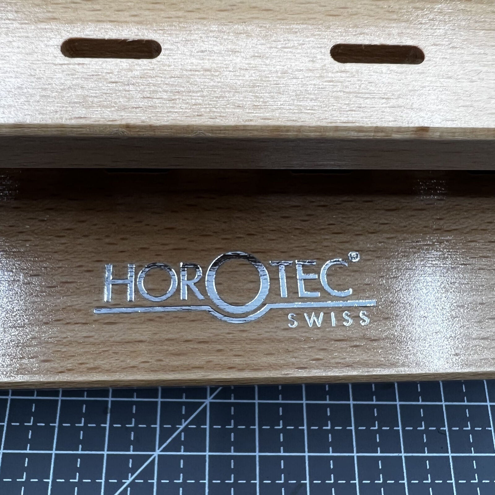 Swiss Horotec wooden rack organizing 12 precision watchmaker tweezers for efficient workspace storage.
