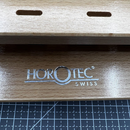 Swiss Horotec wooden rack organizing 12 precision watchmaker tweezers for efficient workspace storage.