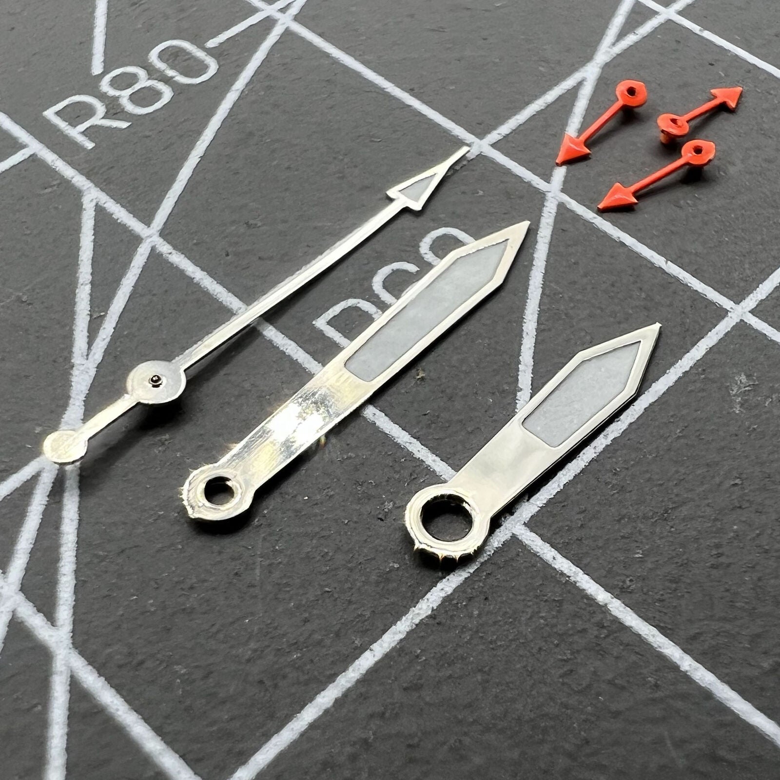 Silver-trimmed green luminous pointed watch hands for Miyota 0S10 movement, enhancing precision and style.