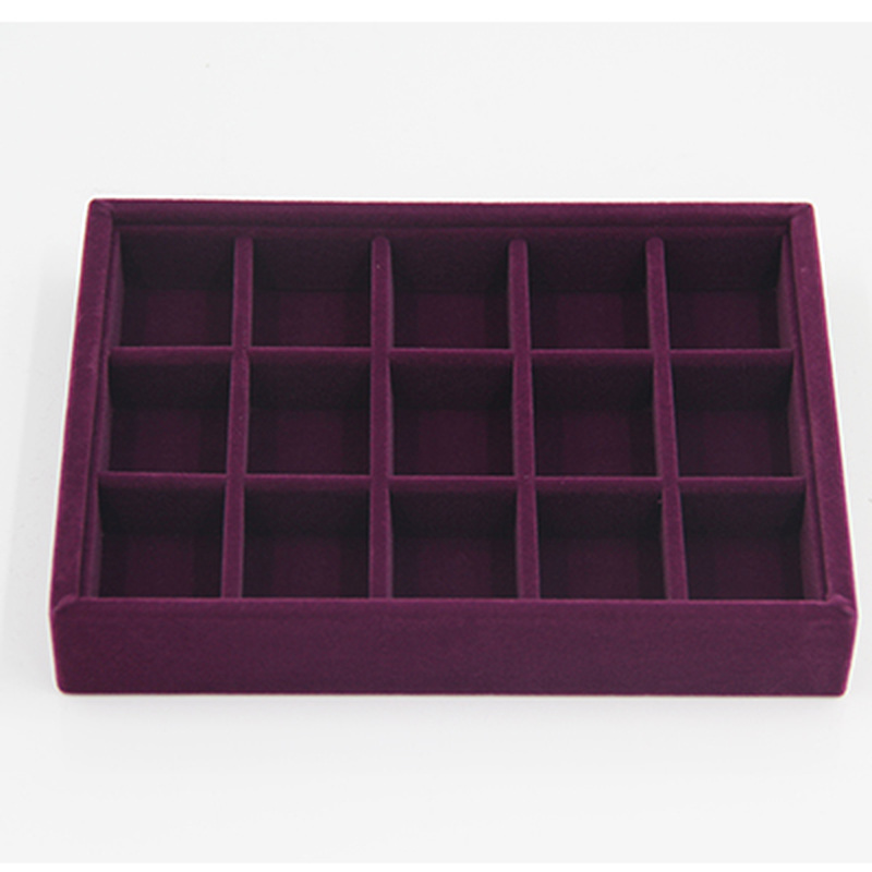 Gray velvet jewelry tray with grid compartments for stackable, elegant storage of watch accessories.